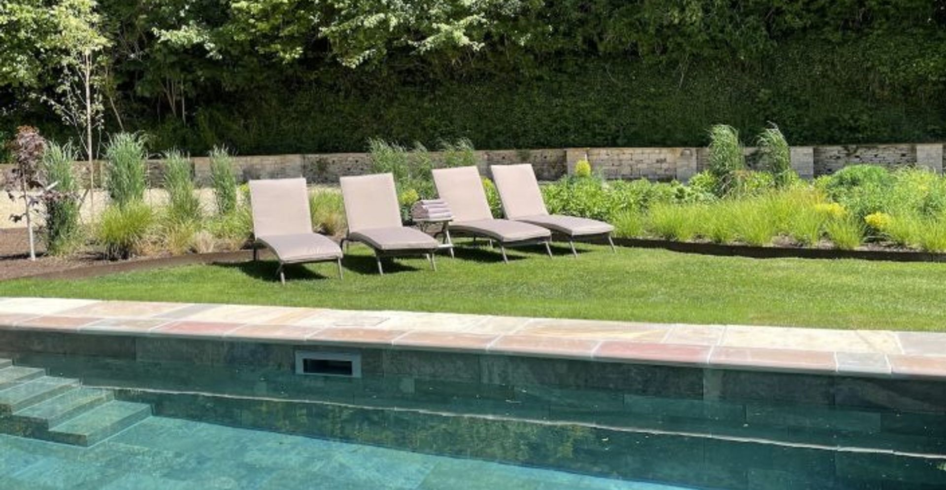 sun loungers resting on the lawn next to a pool