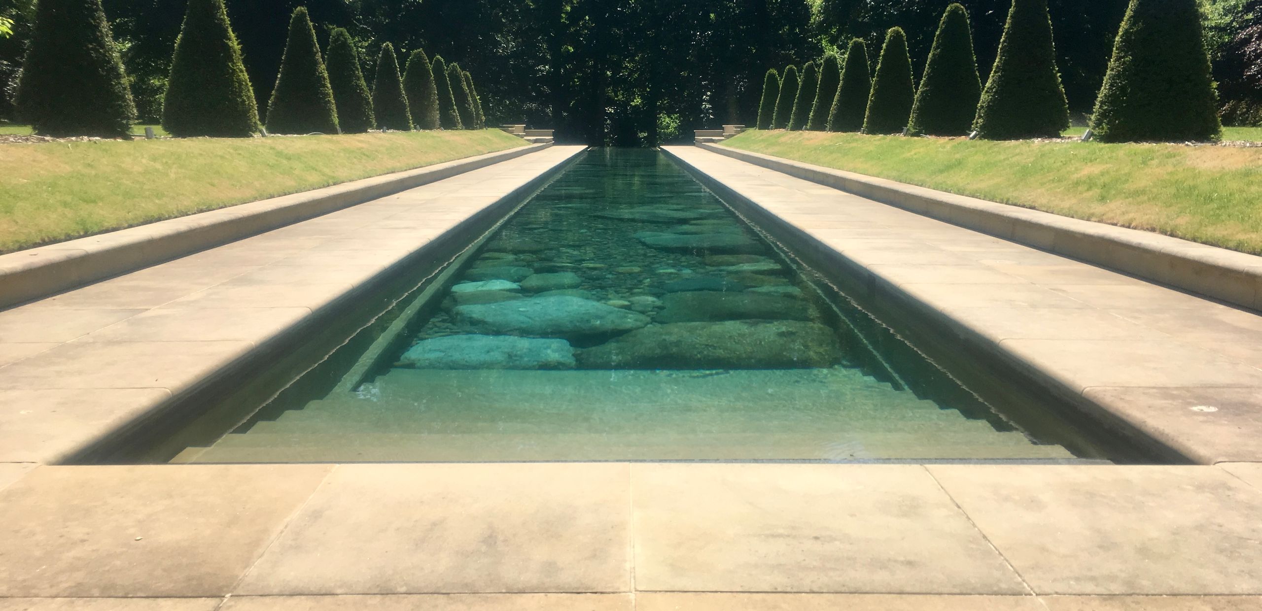 a vast length of swimming pool extends deep into a cotswold garden